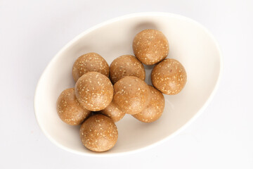 Tilgul Laddu or Til Gul balls for makar sankranti, it's a healthy food made using sesame, crushed peanuts and jaggery. served in a bowl. selective focus showing details.