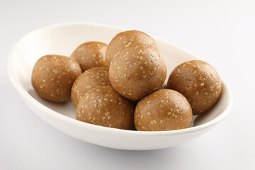 Tilgul Laddu or Til Gul balls for makar sankranti, it's a healthy food made using sesame, crushed peanuts and jaggery. served in a bowl. selective focus showing details.
