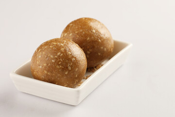 Tilgul Laddu or Til Gul balls for makar sankranti, it's a healthy food made using sesame, crushed peanuts and jaggery. served in a bowl. selective focus showing details.
