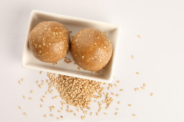 Tilgul Laddu or Til Gul balls for makar sankranti, it's a healthy food made using sesame, crushed peanuts and jaggery. served in a bowl. selective focus showing details.