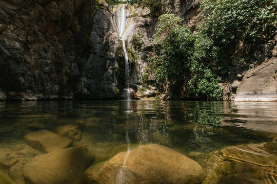 Man jumps from a cliff into a pool near a waterfall