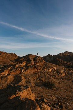 Photographer capturing sunrise from top of mountain in desert