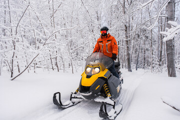 Athlete on a snowmobile moving in the winter forest in the mountains of the Southern Urals