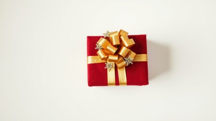 A Single Red Gift Box Decorated with a Gold Bow and Snowflake Accents on a White Background