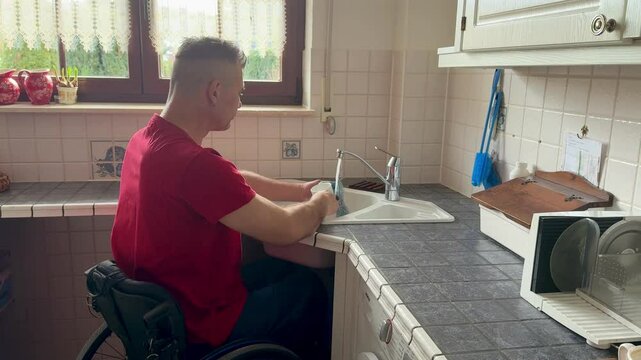 wheelchair user with handicap is washing dishes in the kitchen