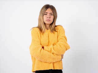 Beautiful caucasian teen girl wearing orange sweater shaking and freezing for winter cold with sad...