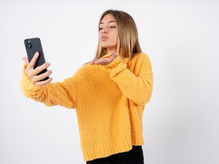 beautiful caucasian teen girl wearing orange sweater Show blank screen smartphone, thumb up recommend new app
