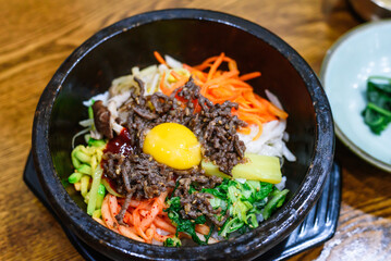 Traditional Korean Dolsot Bibimbap with Raw Egg Yolk in Hot Stone Bowl