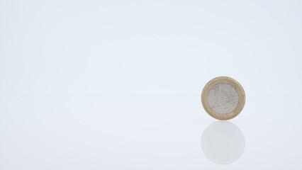 A 1 Euro coin  displayed on a reflective white surface 