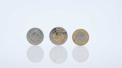 Close-up of 1, 5, and 2 Polish zloty coins arranged on a glossy white surface 