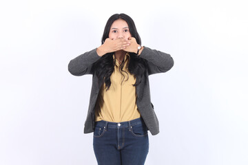 A business asian woman in a gray blazer and yellow shirt is holding her mouth shut