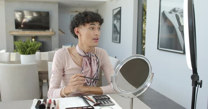 Applying makeup, non binary person using mirror and cosmetics at home
