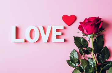 White "LOVE" Letters on Pink Background with Red Heart and Rose, Minimalist Flat Lay Photography Style.