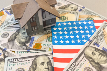  one hundred US dollar bill and a paper cut-out conditional image of a house against the background of the American flag