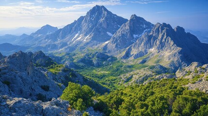 Majestic mountain peak overlooks lush green valley at sunrise.