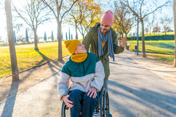 Young man assisting friend in wheelchair enjoying a walk in the park