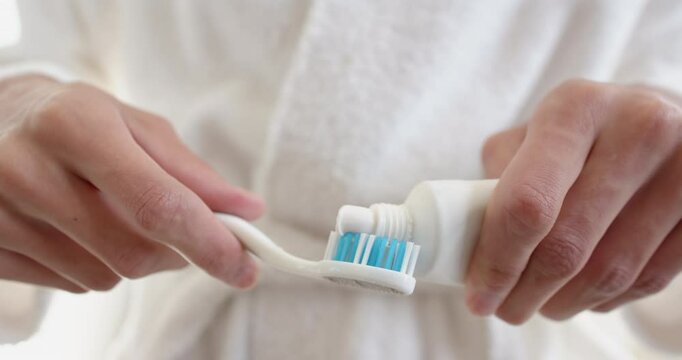 Applying toothpaste on toothbrush, person preparing for morning dental care routine