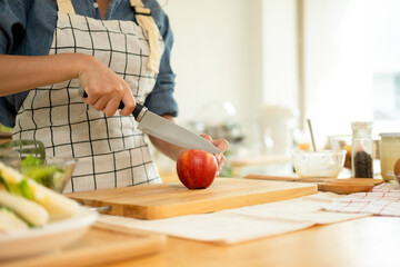A woman cutting an apple in the kitchen