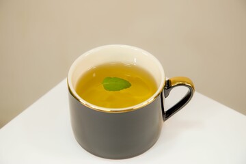 Black mug of herbal tea with green leaf