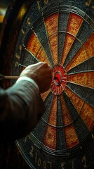 A close-up of a dartboard with a hand aiming to throw a dart at the bullseye.