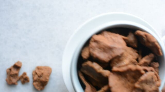 Overhead view of kuli-kuli in a white bowl, top view of nigerian groundnut cakes in a bowl, fresh homemade nigerian kulikuli in a ceramic bowl	