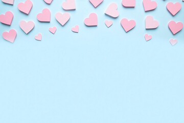Minimalist flat lay with light blue background and pink hearts
