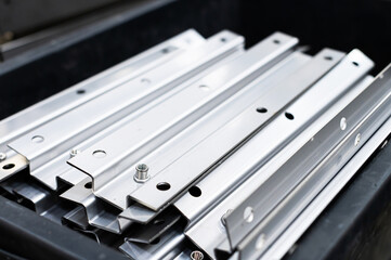 Many precisely bent profile products from stainless steel sheets in a factory or warehouse. Raw...