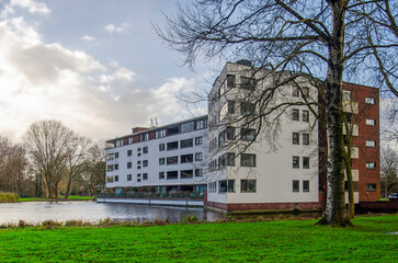 Rotterdam, The Netherlands, December 22, 2024: residential building with brick and plaster facade next to a pond in a suburban park