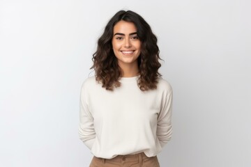 Portrait of a cheerful young businesswoman standing with hands behind back, posing for photo in studio on white background