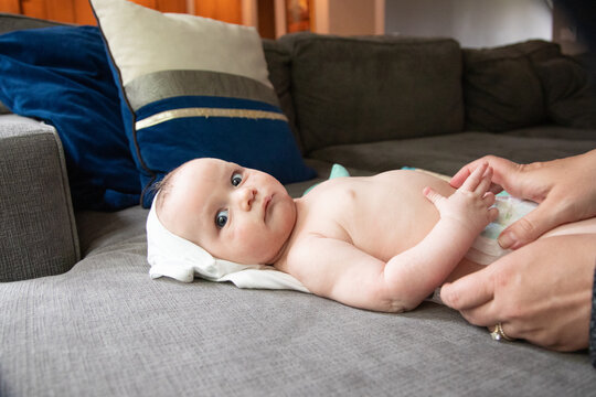 Close-up of a baby boy lying on a sofa having his nappy changed by his mother