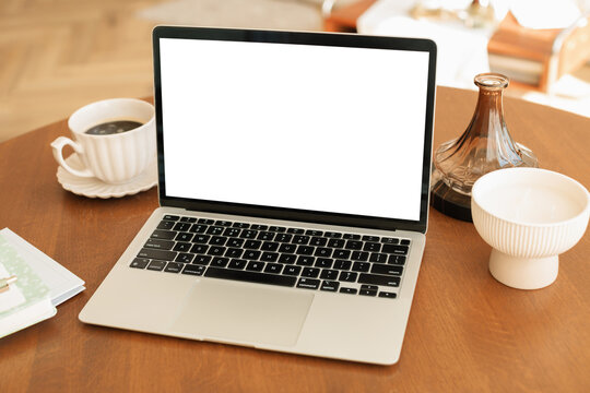Close-up of an open laptop computer with a blank screen and assorted stationery on a home office desk