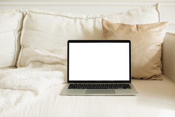 Close-up of an open laptop with a blank screen on a sofa in a stylish living room
