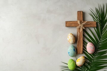 Wooden cross, painted Easter eggs and palm leaf on light grey background, space for text 