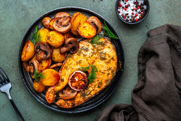 Baked salmon with lemon and dill, fried potatoes with mushrooms and cream sauce. Green rustic background, top view