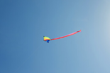 One colorful kite flying in blue sky