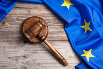 Judge's gavel and flag of European Union on wooden table, top view