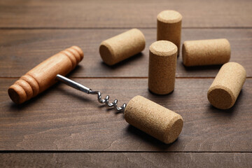 Corkscrew with handle and corks on wooden table