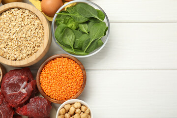 Different products rich in iron on white wooden table, flat lay. Space for text