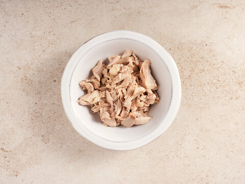 Delicious Spanish Recipe Step Featuring Cooked, Shredded Chicken in a Bowl on a Neutral Surface