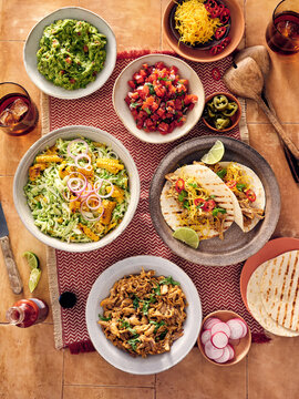 Delicious Mexican Feast Featuring Tacos, Guacamole, Сoleslaw and Fresh Salsa on a Festive Table