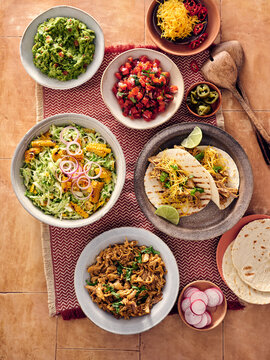 Delicious Mexican Feast Featuring Tacos, Salsa, Сoleslaw and Fresh Guacamole on a Rustic Table Setting