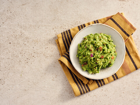 Delicious Guacamole Served in a Bowl on a Striped Napkin, Highlighting Mexican Culinary Traditions