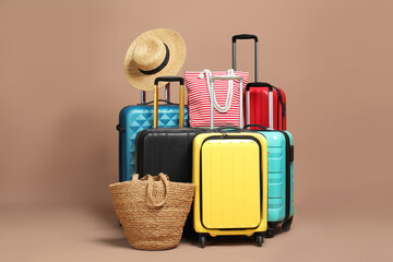 Many colorful suitcases, beach bags and straw hat on beige background