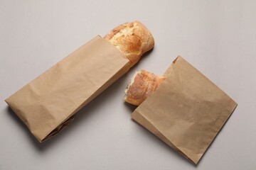 Paper bags with fresh baguettes on gray table, top view
