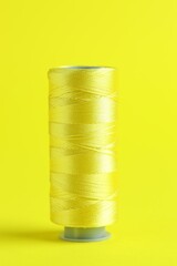 Spool of sewing thread on yellow background