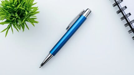 A sleek blue pen rests on a clean surface beside a small green plant and a spiral notebook, creating a fresh, minimalistic workspace aesthetic.