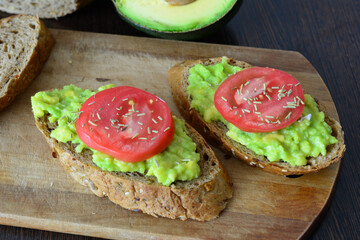 two avocado toasts with tomato slices on the cutting board close up keto diet   