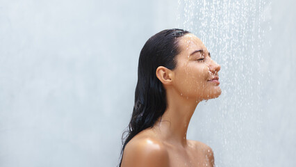 A woman with wet hair enjoys a refreshing shower, her eyes closed in a moment of pure relaxation. The soothing water cascades over her, capturing the essence of tranquility and self-care, perfect for