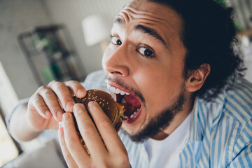 Young man enjoying a tasty burger at home in a relaxed and cozy setting