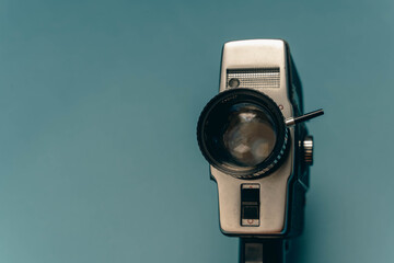 A classic film camera positioned against a blue backdrop